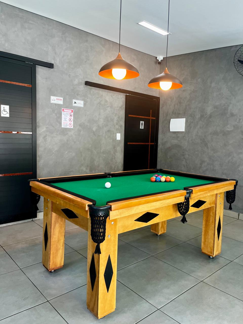 Salão de jogos com mesa de bilhar e iluminação pendente